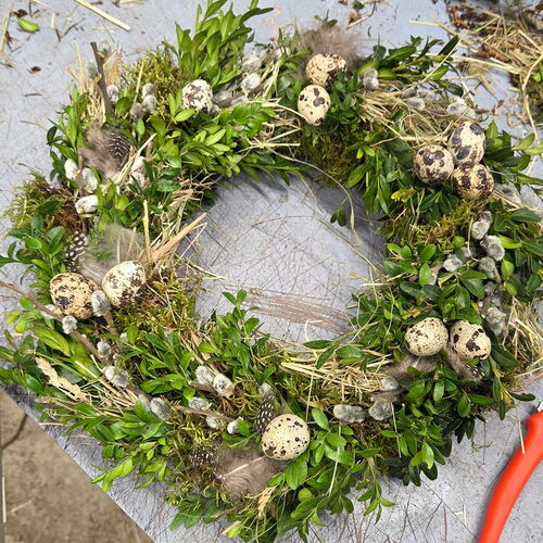 Fertiger Kranz aus Moos, Heu und Buchsbaum liegt auf dem Tisch